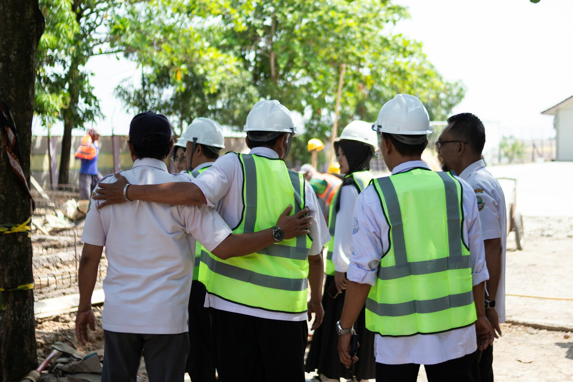 Team of workers wearing white hard hats and hi-vis safety vests on site