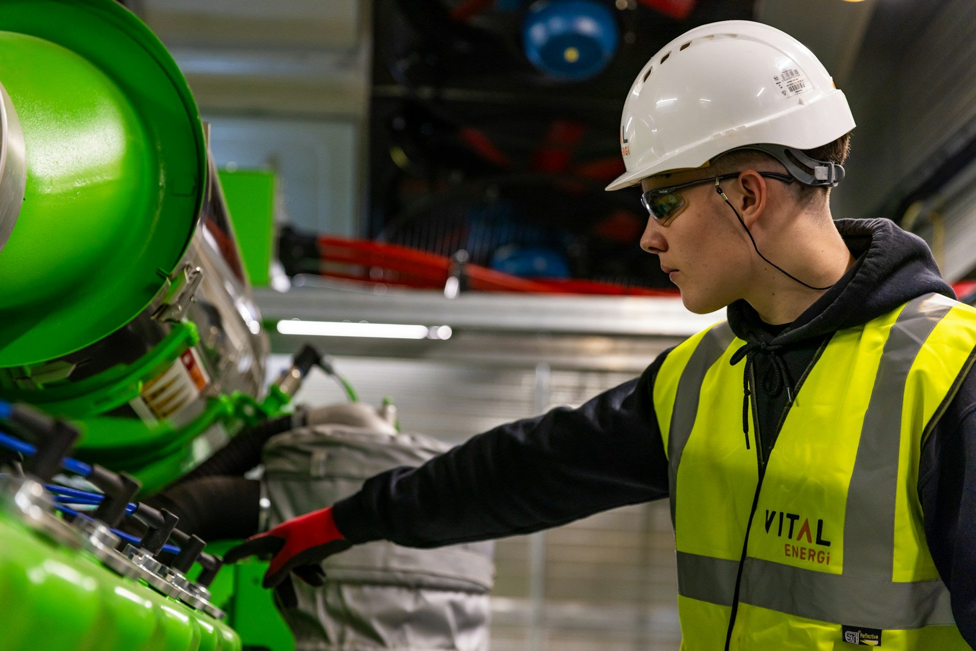 Worker wearing a hard hat, safety glasses, hi-vis vest and protective gloves