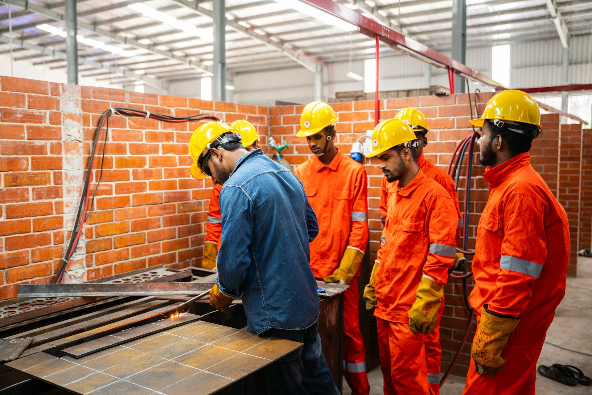 Workers in hard hats, coveralls, goggles and gloves in an industrial workshop